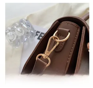 Macro shot of durable gold-tone metal hardware and lobster clasp on dark brown handbag
