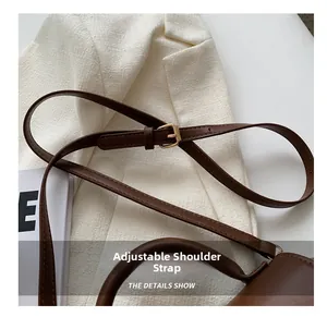 Detailed macro view of the adjustable dark brown leather shoulder strap with metal buckle