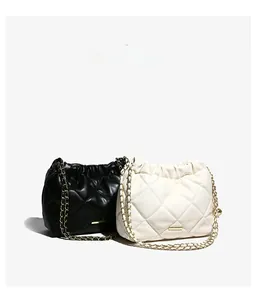Close-up of quilted chain bags in black and beige with drawstring and gold metal strap