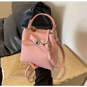Detailansicht der rosa Eimer-Handtasche aus Leder mit Silberverschluss auf Stein