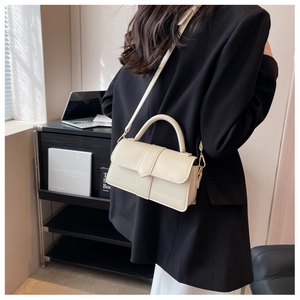 Creamy leather flap handbag shown on person wearing a black blazer in office setting