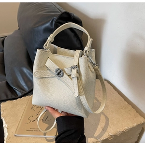 Detail der cremeweißen Eimer-Tasche aus Leder mit litchi-Narbung und silbernem Drehschloss