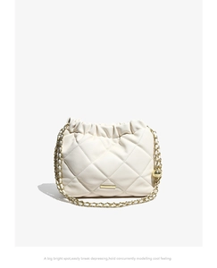 Detail of white quilted bucket bag featuring drawstring closure and gold ball chain