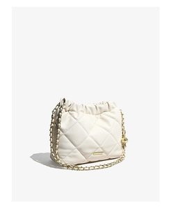 Detail of white quilted bucket bag with gold chain strap and elegant metallic sphere