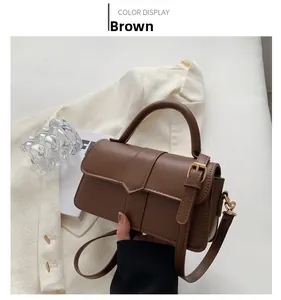 Detailed view of a brown faux leather handbag featuring gold buckles and a top handle