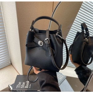 Nahaufnahme der schwarzen Bucket Bag mit Litschiprägung, Metallverschluss und Griff