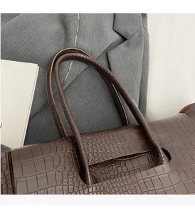Close-up of durable handles and crocodile texture on a brown tote bag