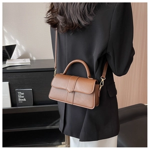 Brown leather crossbody handbag shown on model with adjustable strap and top handle