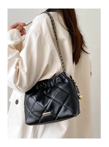 Detail of black quilted leather bucket bag featuring gold chain and drawstring closure