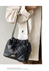 Close-up of black quilted leather bucket bag with gold hardware and chain strap