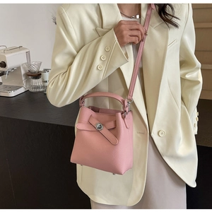 Detail der rosa Eimertasche aus Litschi-Leder mit Metalldrehverschluss und Gurt
