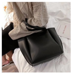 Vue détaillée du grand sac cabas noir avec texture en cuir et bandoulières minimalistes
