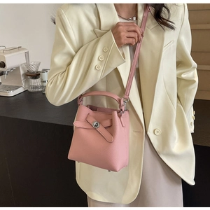 Rosa Eimer-Handtasche aus Leder mit Schleife und Metalldrehverschluss am Modell