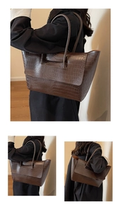 Detail view of large dark brown tote bag featuring embossed crocodile stone texture leather