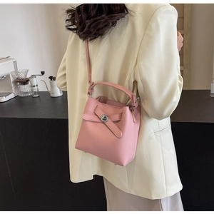 Rosa Beuteltasche aus Leder mit Kieselprägung, getragen über einem beigen Anzug