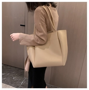 Gros plan d'un sac cabas minimaliste abricot montrant la texture du cuir souple et la poche