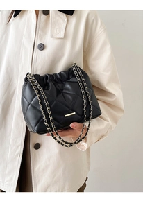 Detail of a black quilted chain bag with gold hardware and soft cloud-style texture
