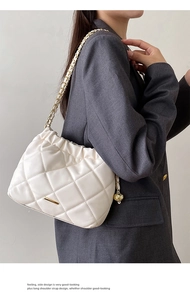 Detail of white quilted bucket bag with gold chain strap and metallic ball charm on model