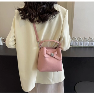 Mini-Eimertasche aus rosafarbenem Leder mit Narbung und Schnallendetail an einem Modell