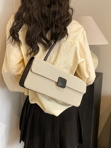 Detail of cream woven baguette bag with brown leather trim and shoulder strap on model