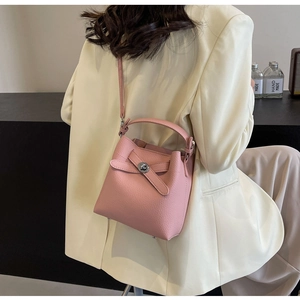 Rosa Eimer-Handtasche aus genarbtem Leder mit Silberverschluss vor beigem Blazer