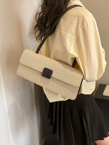 Detail of light beige woven baguette bag with black shoulder strap and square buckle detail