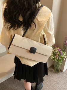 Detail of minimalist beige baguette bag with black leather strap and matte square buckle