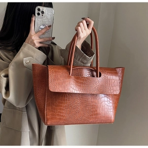 Detail of dark brown stone pattern tote bag carried by model in a khaki trench coat
