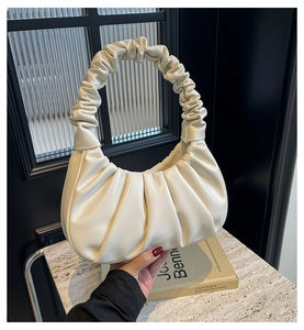 Detail of off-white ruched handbag with scrunchie handle and pleated PU leather texture