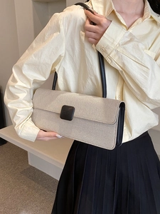 Detail view of beige woven baguette bag with a square buckle and black leather strap
