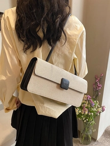 Close-up of beige textured baguette bag with black trim and vintage square buckle detail