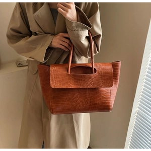 Detail of vintage brown tote bag featuring crocodile stone texture and sturdy handles