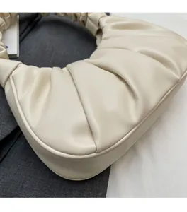 Detailed view of cream pleated underarm hobo bag highlighting soft synthetic leather texture