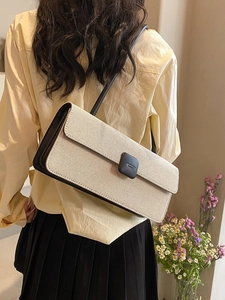 Shoulder baguette bag in beige canvas with black leather trim shown on model shoulder