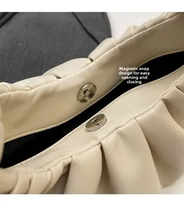 Detail of light beige pleated cloud bag showing convenient magnetic buckle closure