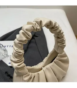 Detail of the soft pleated texture and comfortable handle on a beige cloud bag