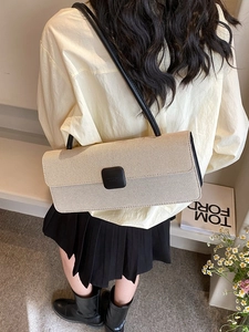 Detail of woven beige baguette bag with black buckle and strap on a model shoulder