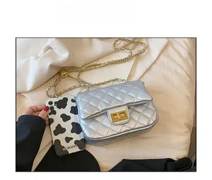 Size comparison of silver quilted flap chain bag with golden lock next to a smartphone