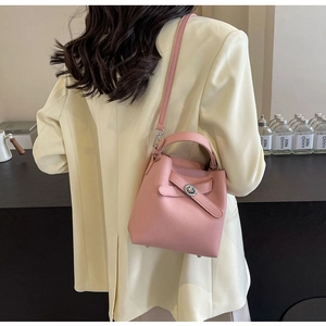 Detailansicht der Rückseite einer rosa Eimer-Tasche aus Leder mit Griff und Gurt