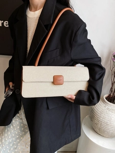 Detail of woven cream fabric baguette bag with brown leather strap on black blazer