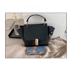 Detail view of black trapezoidal wing bag with crocodile pattern and gold hardware lock