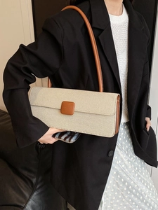 Close-up of a stylish canvas baguette bag featuring brown leather trim and metal clasp
