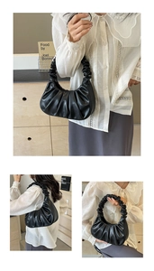Detail of black pleated cloud bag with scrunched handle and moon-shaped design texture