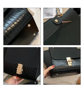 Detail of matte black wing handbag with gold lock and crocodile pattern leather texture