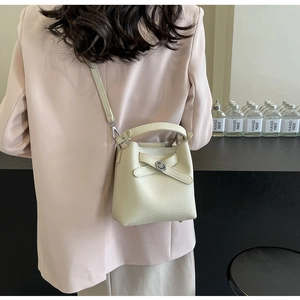 Cremeweiße Beuteltasche mit Litschi-Struktur am Model zur Darstellung der Größe
