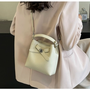 Detailansicht der cremefarbenen Leder-Beuteltasche mit silbernen Beschlägen am Blazer