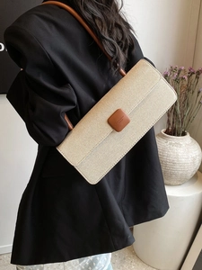 Detail of beige woven baguette bag featuring brown leather buckle and strap