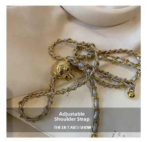 Detail of adjustable gold metal chain strap woven with grey leather and quilted ball slider