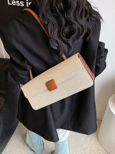 Detailed back view of a beige woven baguette bag on a model wearing a black blazer