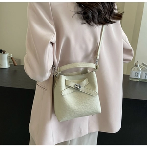 Modell mit cremefarbener Eimer-Tasche aus Leder mit Lychee-Muster und Schultergurt